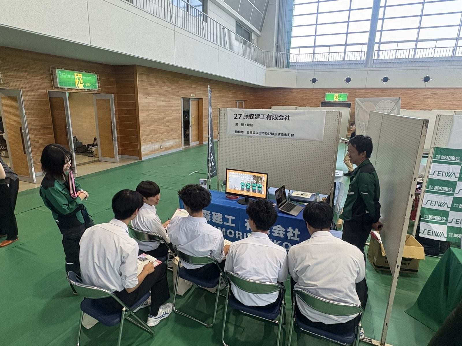 就職企業説明会のブースで高校生に仕事の内容を説明する藤森建工スタッフ